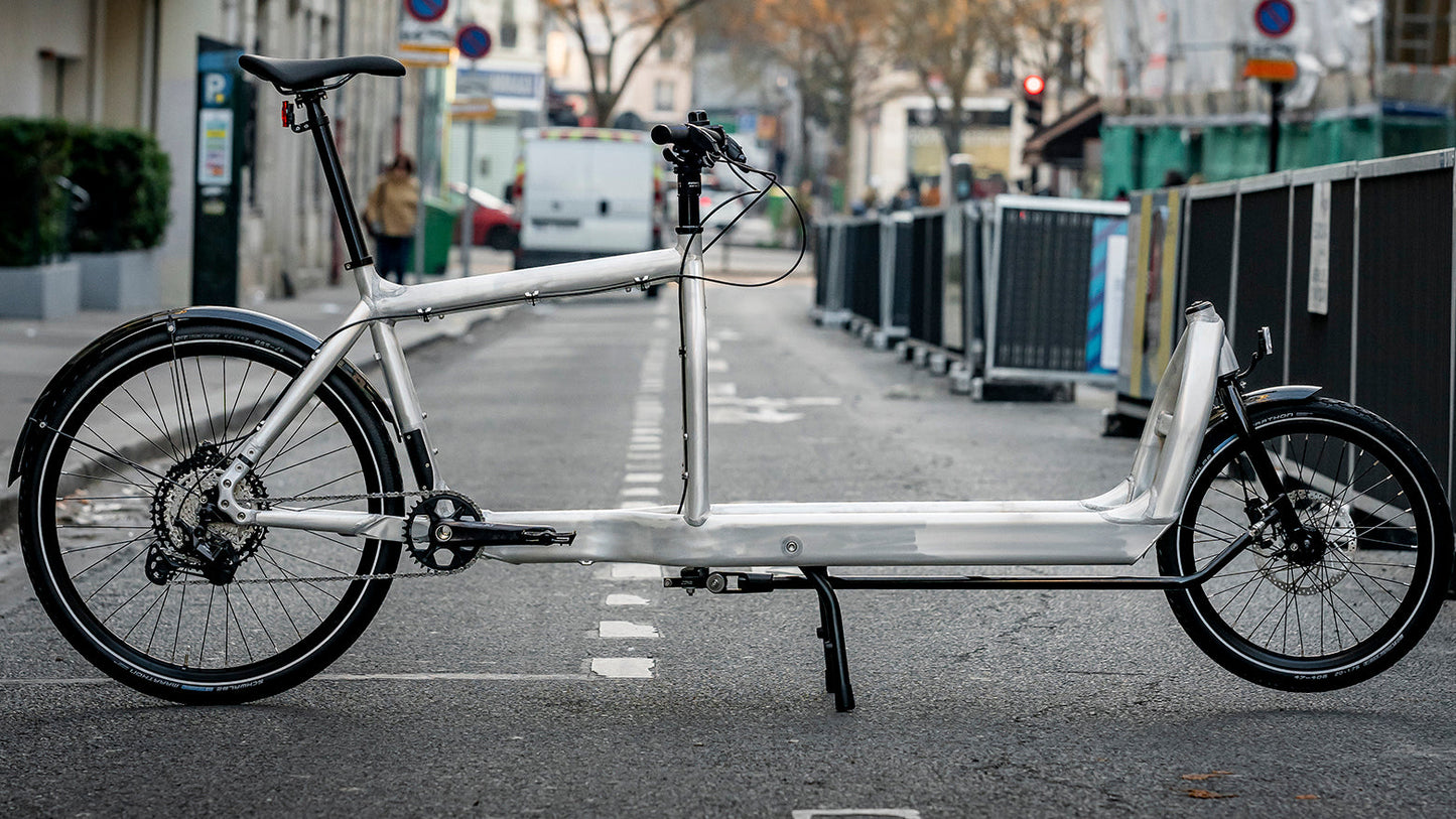 Bullitt cargo bike in Raw Unpainted Aluminum on a city street