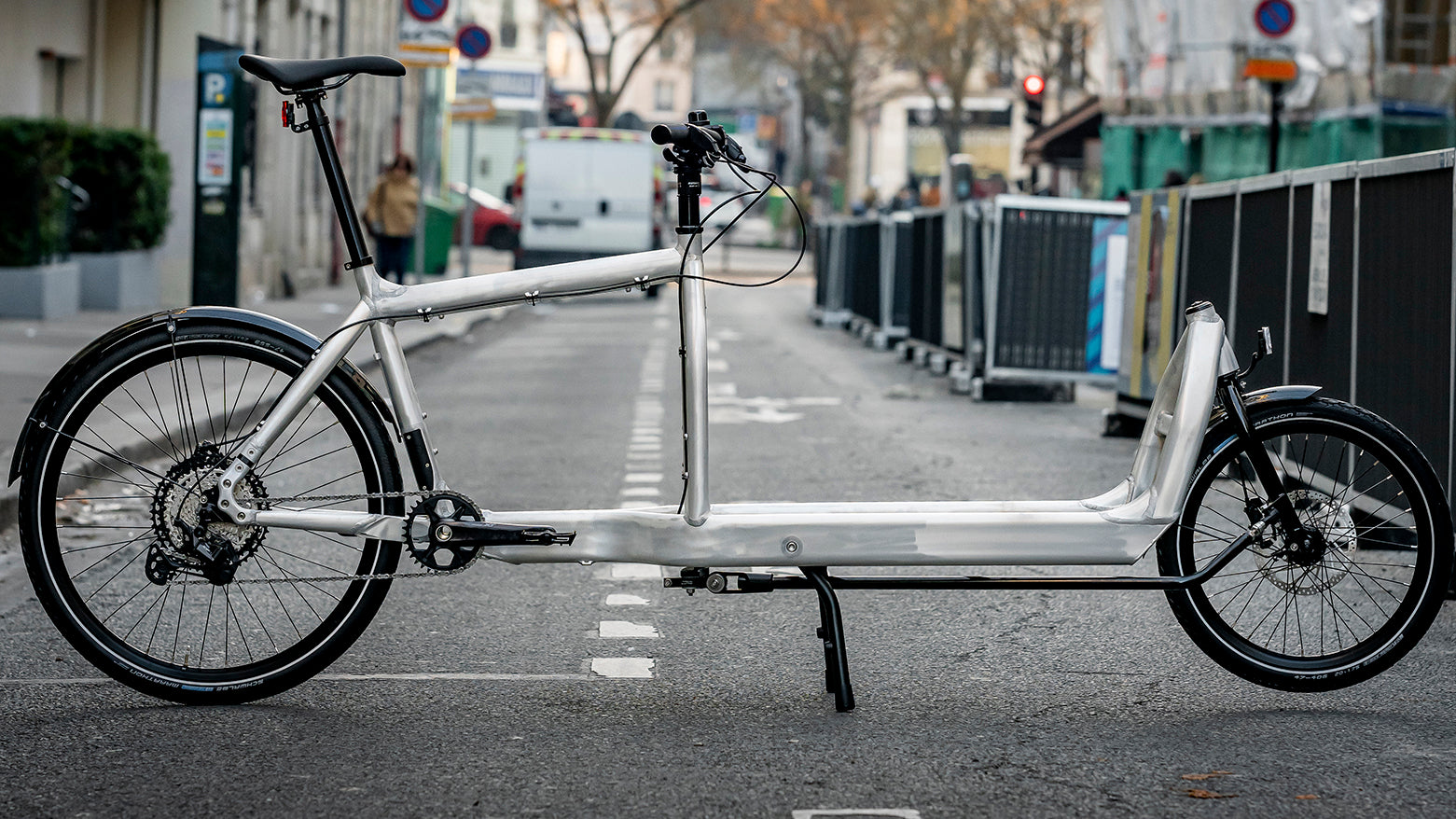 Bullitt cargo bike in Raw Unpainted Aluminum on a city street